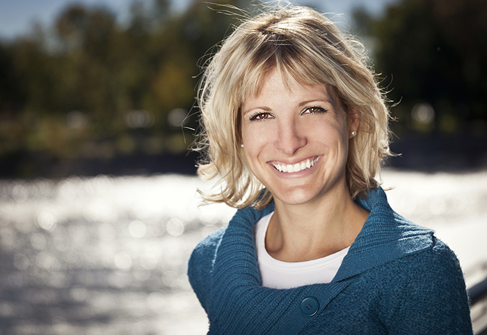 Happy, incredible smile, blonde woman by lake incredible smiles; Dr Alyssa Ellsworth, DDS specializing in cosmetic dentistry and general dentistly Incredible Smiles; DDS specializing in cosmetic dentistry serving the Front Range, CO call 303-499-0013
